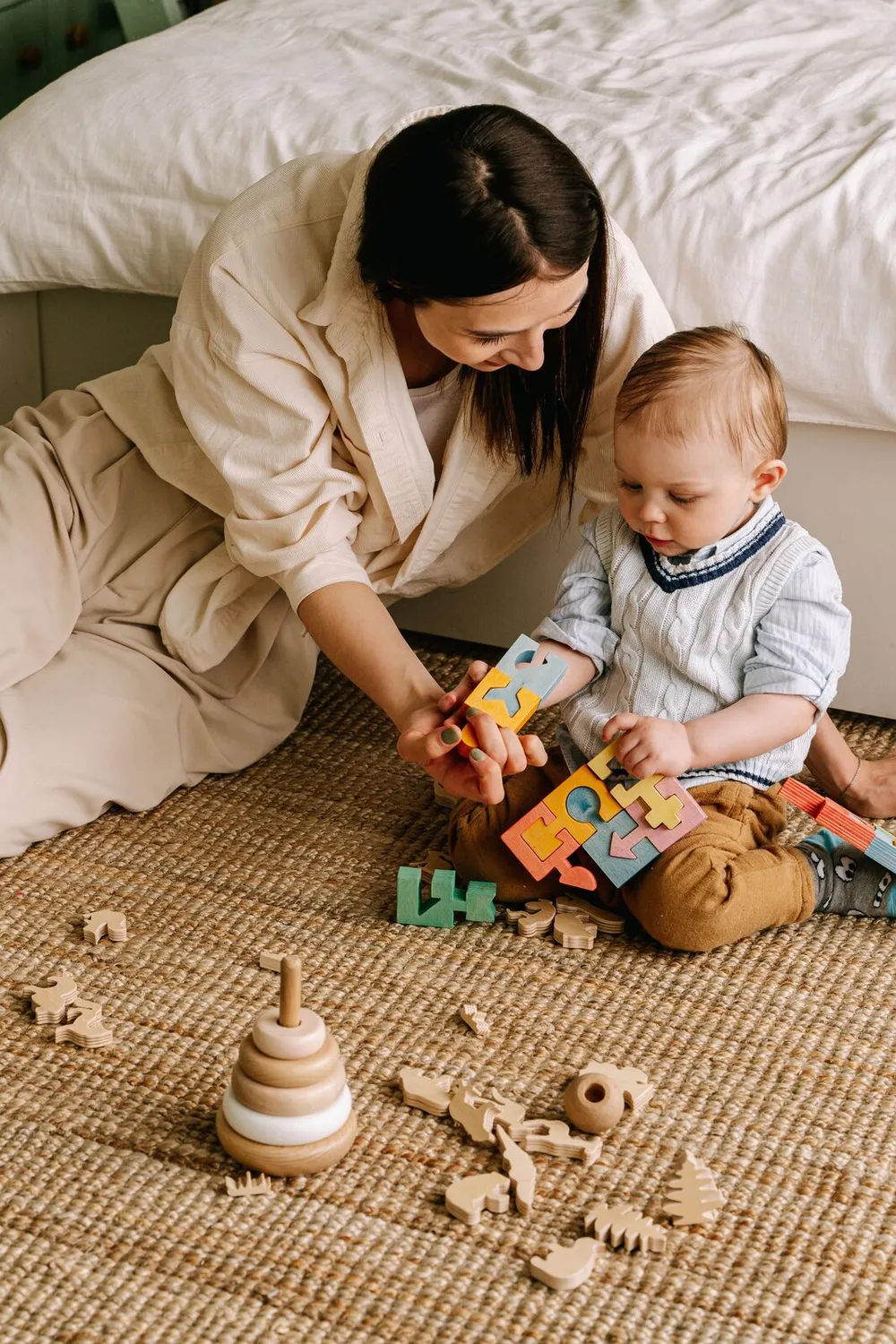 Mãe sentada no tapete brincando com o filho pequeno com brinquedos de madeira